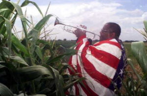 Rev. Ronald V. Myers, Sr., M.D. Chairman, National Juneteenth Holiday Campaign playing the trumpet in a corn field