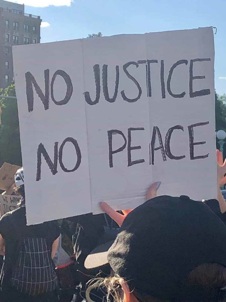 Protest with sign saying "No justice no peace"